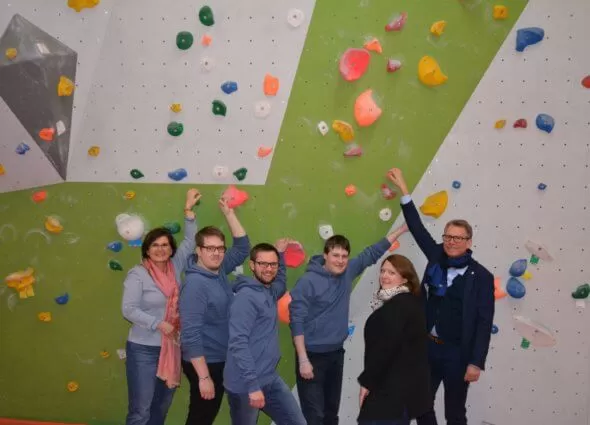 Sechs Personen vor einer Kletterwand