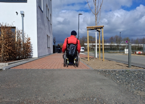 Mensch im Rollstuhl auf unwegsamer Straße